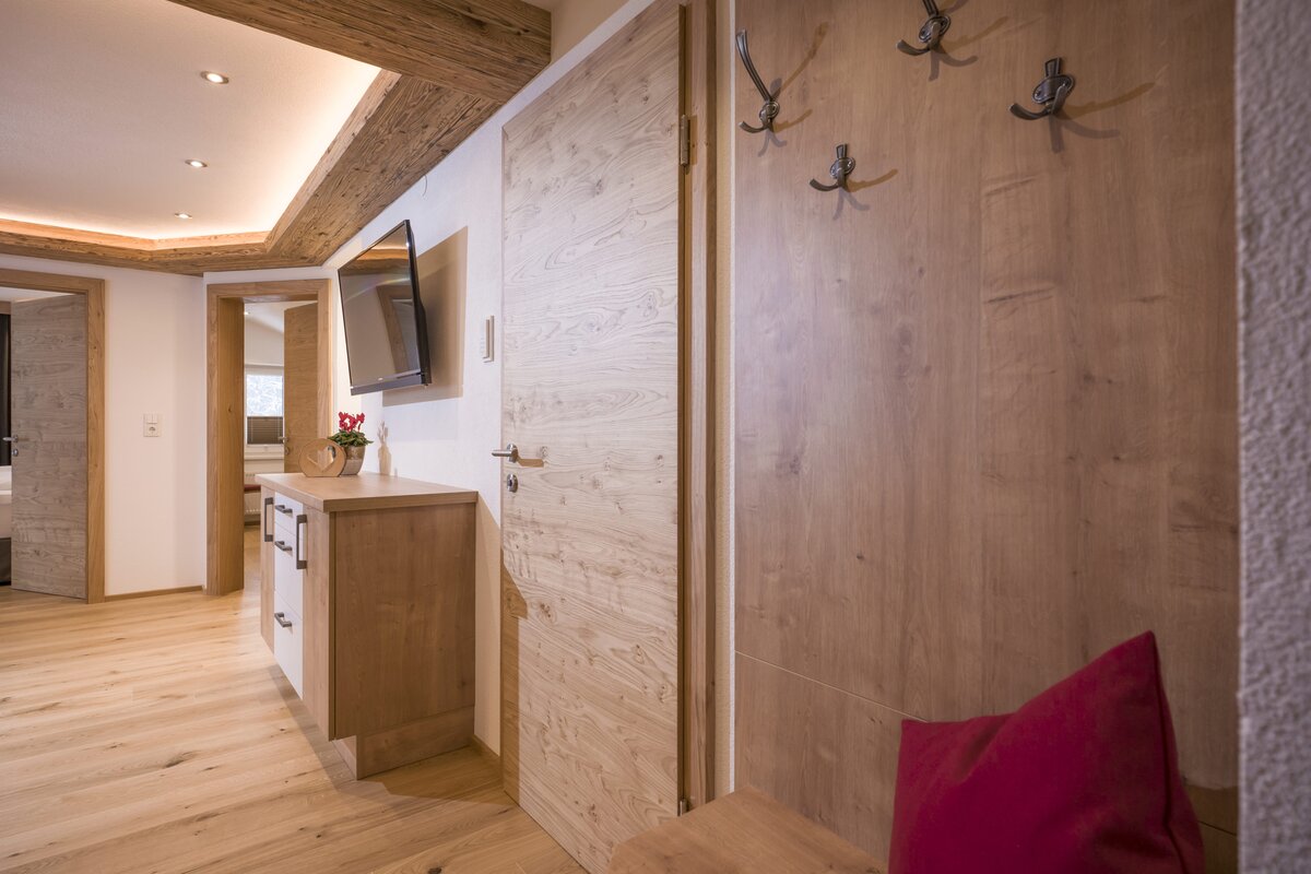 Ein einladender Flur mit Holzfußboden und einem roten Kissen, perfekt für ein gemütliches Appartement. 