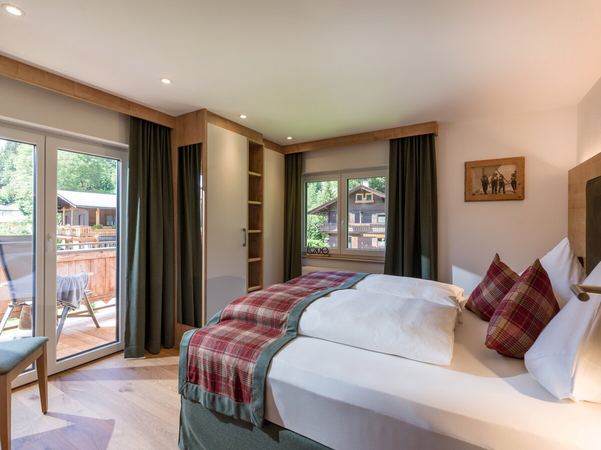 Gemütliches Schlafzimmer mit Bett und Balkon, der die atemberaubende Berglandschaft zeigt. 