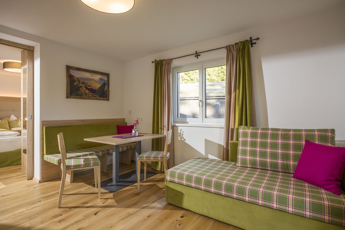 Wohnzimmer mit einer grünen Couch und einem Tisch, gemütlich und einladend, ideal für entspannte Abende im Appartement.